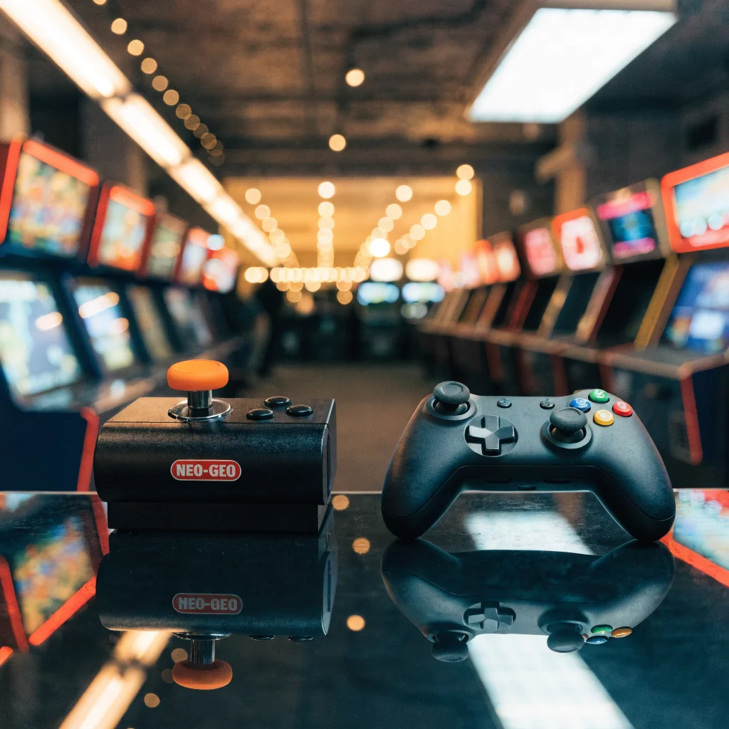 Neo Geo Arcade Stick Pro next to game controller, retro and modern gaming gear